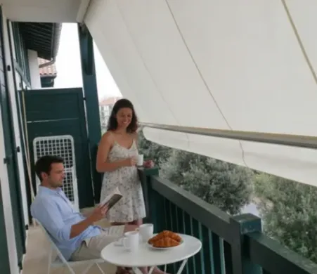 Pareja disfrutando de balcon y desayuno con toldo stor desplegado