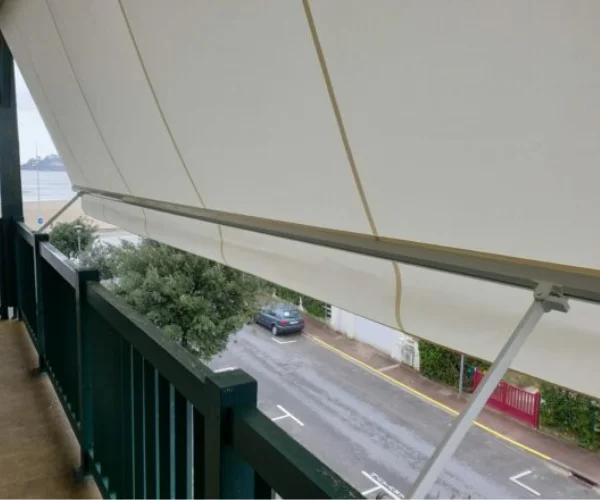 Toldo Stor desplegado e inclinado Familia disfrutando del balcón con cortinas de cristal pamplona